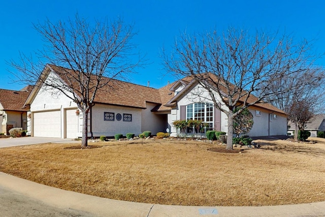 ranch-style home featuring stucco siding, an attached garage, concrete driveway, and a front yard