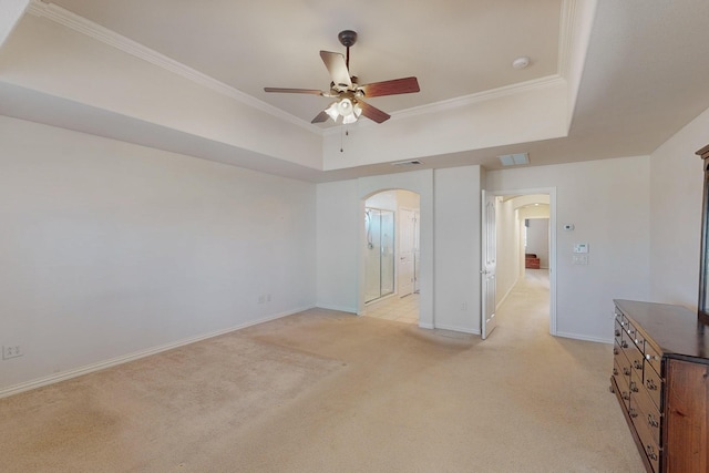 unfurnished bedroom featuring visible vents, light carpet, ornamental molding, a tray ceiling, and arched walkways