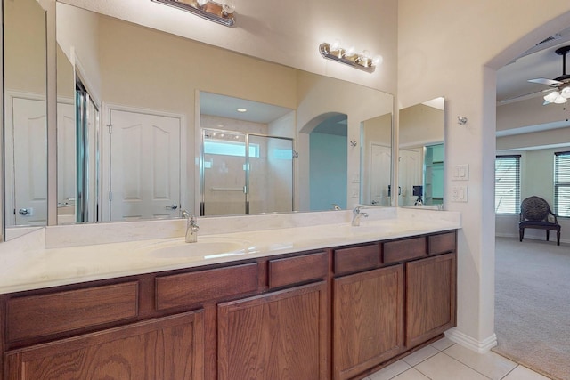 full bath with double vanity, a ceiling fan, a stall shower, and a sink