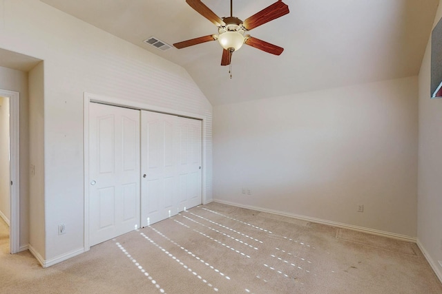 unfurnished bedroom featuring lofted ceiling, visible vents, a closet, and light carpet