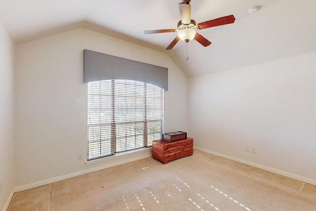 carpeted empty room featuring lofted ceiling, a ceiling fan, and baseboards