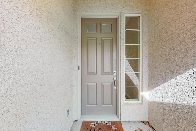 doorway to property featuring stucco siding