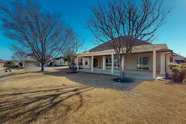 back of property featuring a patio area, a lawn, and stucco siding