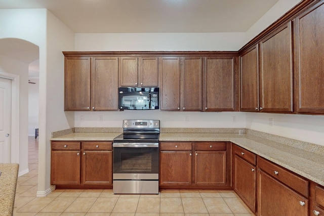 kitchen with light tile patterned floors, stainless steel electric range oven, arched walkways, and black microwave