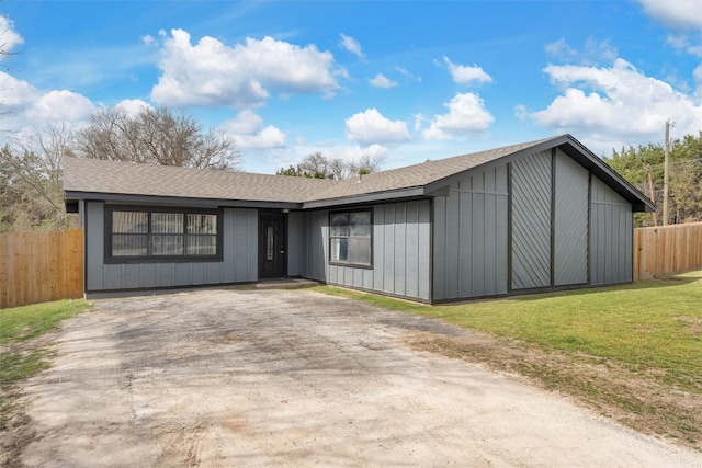 view of front of house featuring a front yard, fence, driveway, a shingled roof, and board and batten siding