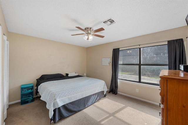 bedroom featuring baseboards, visible vents, ceiling fan, a textured ceiling, and light carpet