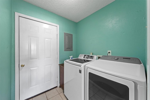 clothes washing area featuring electric panel, a textured ceiling, washing machine and dryer, light tile patterned floors, and laundry area