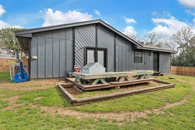 back of house featuring a garden, board and batten siding, a yard, and fence