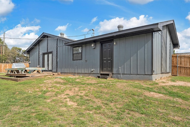 back of property featuring a lawn, board and batten siding, a deck, and fence