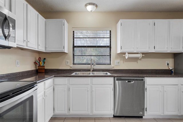 kitchen featuring a sink, white cabinets, appliances with stainless steel finishes, a textured ceiling, and dark countertops