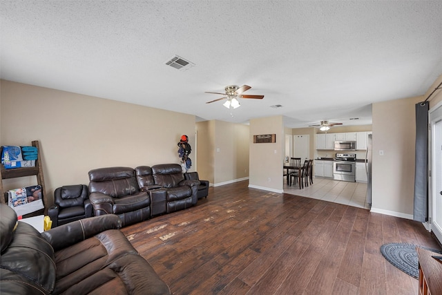 living area with visible vents, a textured ceiling, a ceiling fan, and hardwood / wood-style floors