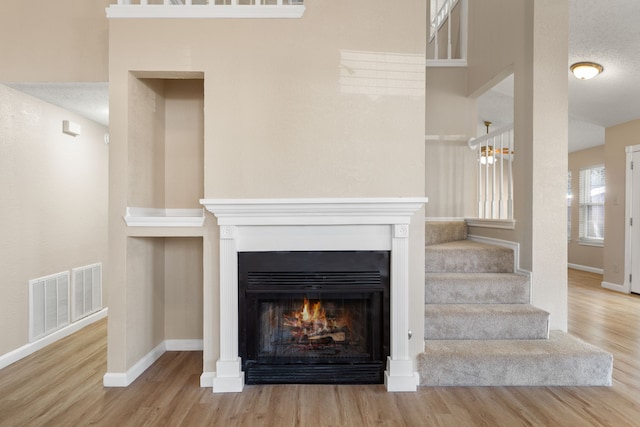 interior space featuring visible vents, a warm lit fireplace, baseboards, and wood finished floors