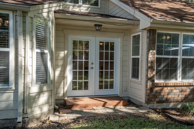 property entrance with stone siding, french doors, and a shingled roof