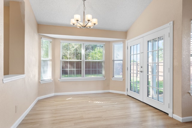 interior space featuring a notable chandelier, a textured ceiling, lofted ceiling, and light wood-style floors