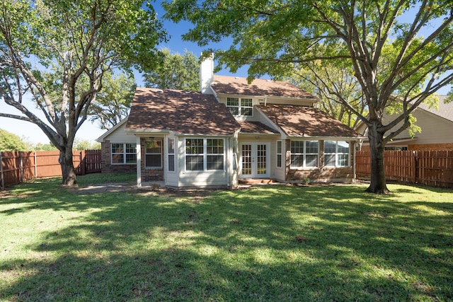 rear view of house featuring a yard, french doors, a fenced backyard, and a chimney