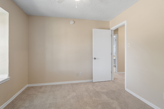 carpeted spare room featuring baseboards, a textured ceiling, and a ceiling fan