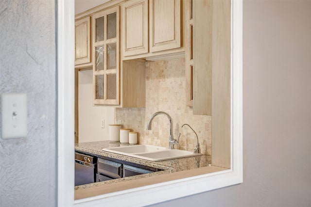 kitchen with a sink, light countertops, glass insert cabinets, dishwasher, and tasteful backsplash