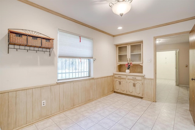 unfurnished room with crown molding, wood walls, and wainscoting