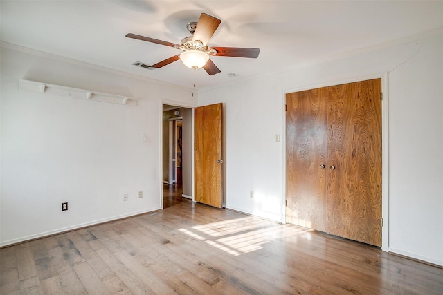 unfurnished bedroom featuring visible vents, ornamental molding, wood finished floors, a closet, and baseboards