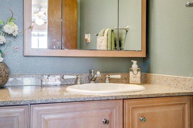 bathroom featuring vanity and a textured wall