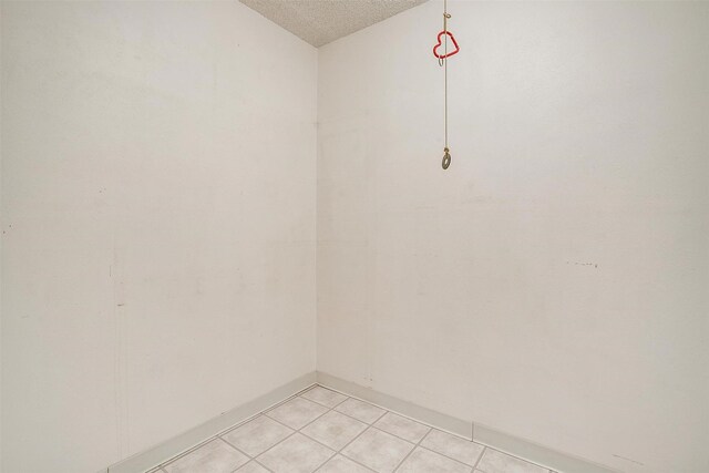 empty room with light tile patterned floors and a textured ceiling