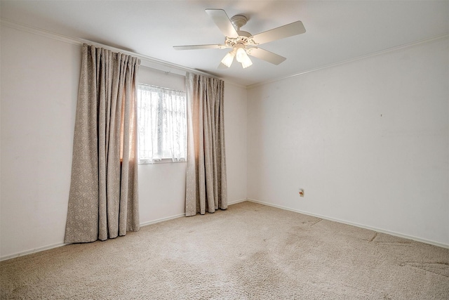 carpeted spare room with baseboards, a ceiling fan, and ornamental molding