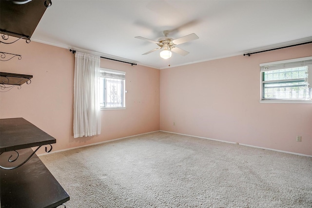 interior space with baseboards, carpet floors, a ceiling fan, and crown molding