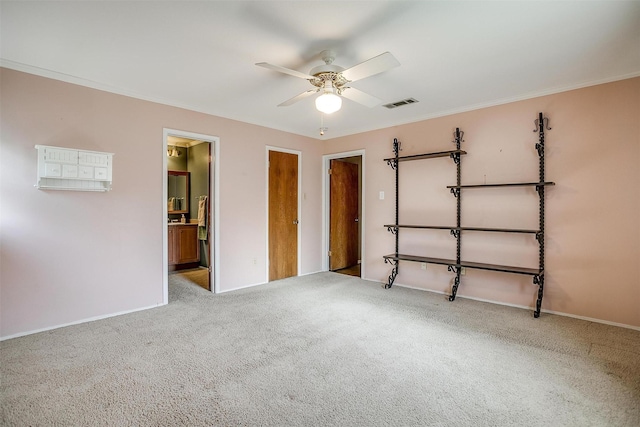 unfurnished bedroom with visible vents, ceiling fan, baseboards, ornamental molding, and carpet floors