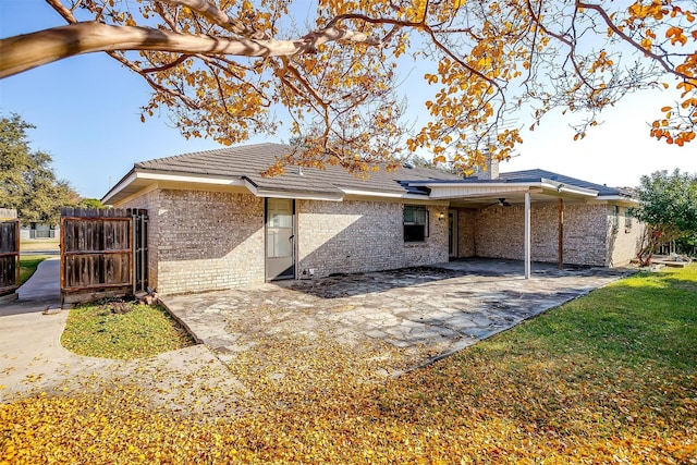 back of property with fence, a ceiling fan, a yard, a patio area, and brick siding