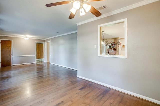 spare room featuring visible vents, ornamental molding, baseboards, and wood finished floors