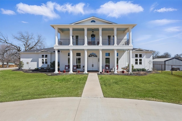 neoclassical home featuring a porch, a balcony, and a front yard