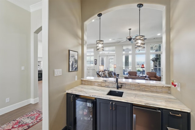 bar featuring beverage cooler, a ceiling fan, a sink, wood finished floors, and baseboards