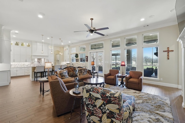 living room with crown molding, baseboards, ceiling fan, recessed lighting, and wood finished floors