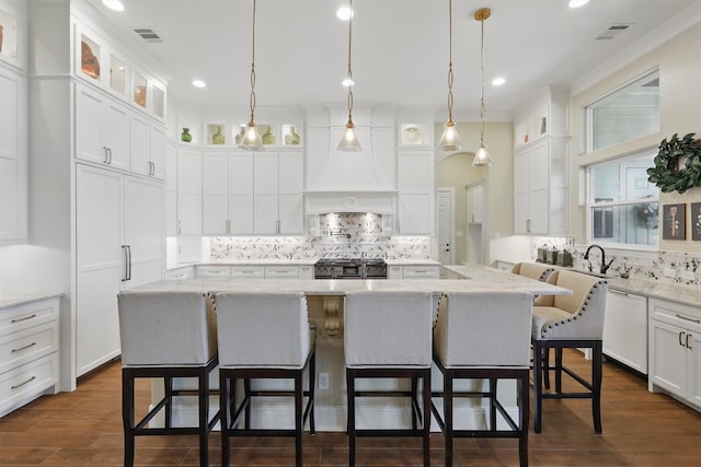 kitchen with visible vents, range with two ovens, white dishwasher, white cabinetry, and a center island