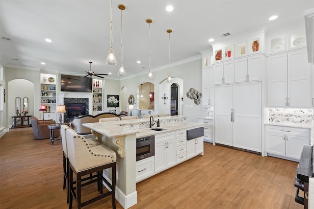 kitchen with visible vents, arched walkways, a ceiling fan, and crown molding