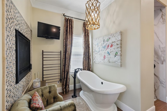 bathroom featuring a soaking tub, ornamental molding, baseboards, and wood finished floors