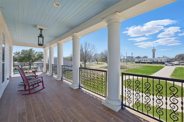 wooden terrace featuring a porch and a yard