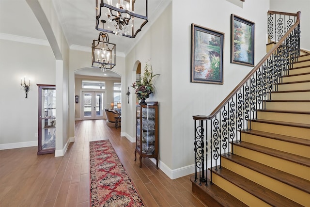 entrance foyer featuring stairs, wood finished floors, arched walkways, and a chandelier