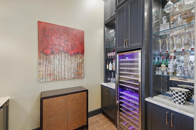 bar featuring baseboards, wine cooler, and a dry bar