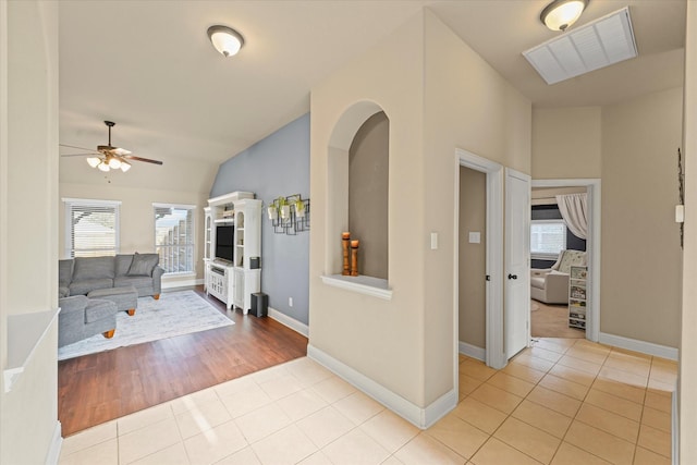 interior space with baseboards, lofted ceiling, visible vents, and ceiling fan