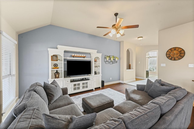 living area with dark wood-type flooring, baseboards, ceiling fan, lofted ceiling, and arched walkways