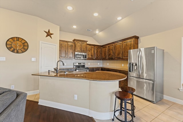 kitchen featuring visible vents, an island with sink, a sink, appliances with stainless steel finishes, and backsplash