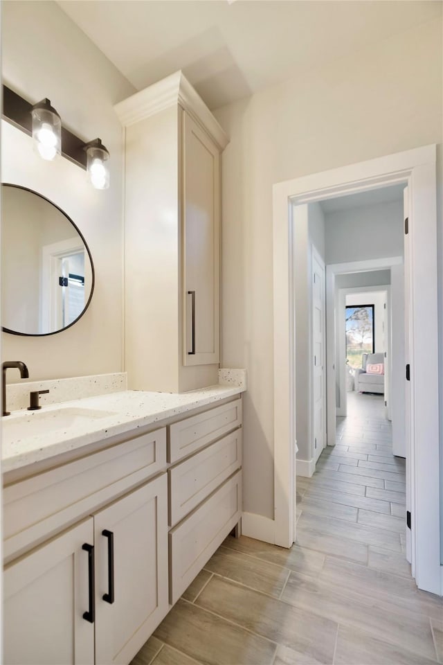 bathroom with wood finish floors, baseboards, and vanity