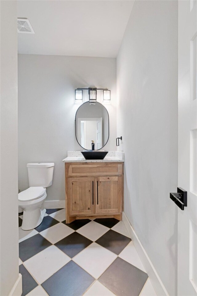 bathroom with tile patterned floors, visible vents, toilet, baseboards, and vanity