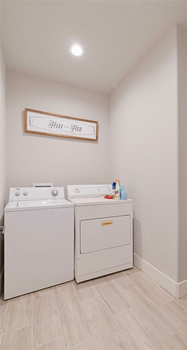 laundry area featuring baseboards, wood tiled floor, laundry area, and washer and clothes dryer