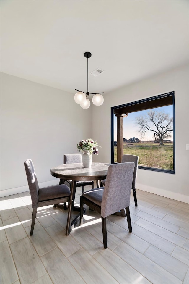 dining area featuring a chandelier, visible vents, baseboards, and wood tiled floor