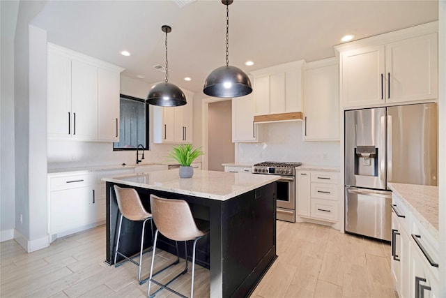 kitchen with light stone counters, appliances with stainless steel finishes, a center island, and light wood-style floors