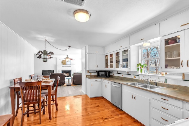 kitchen featuring a sink, dishwasher, a fireplace, and light wood finished floors