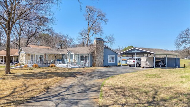 view of front of property featuring a carport, driveway, a chimney, and a front lawn