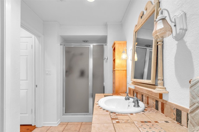 full bath with a shower stall, ornamental molding, tile patterned floors, and a sink